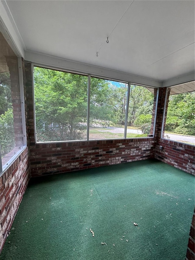 unfurnished sunroom with brick wall, carpet flooring, and healthy amount of natural light