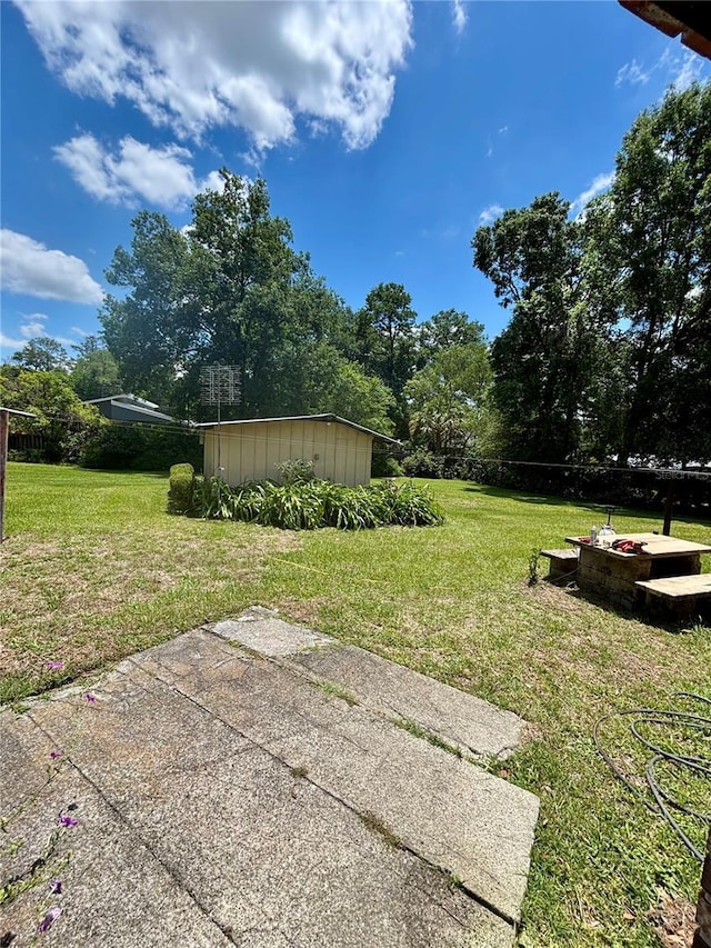 view of green lawn with a storage unit and an outbuilding