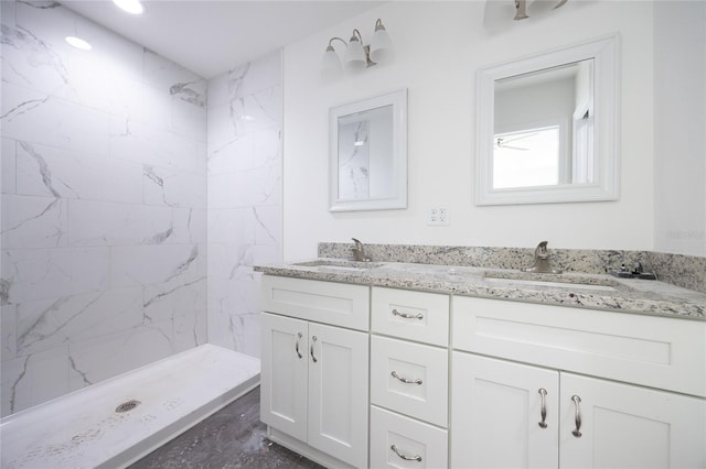 bathroom with tiled shower and double vanity