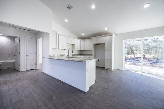 kitchen featuring a sink, a peninsula, light stone countertops, recessed lighting, and vaulted ceiling