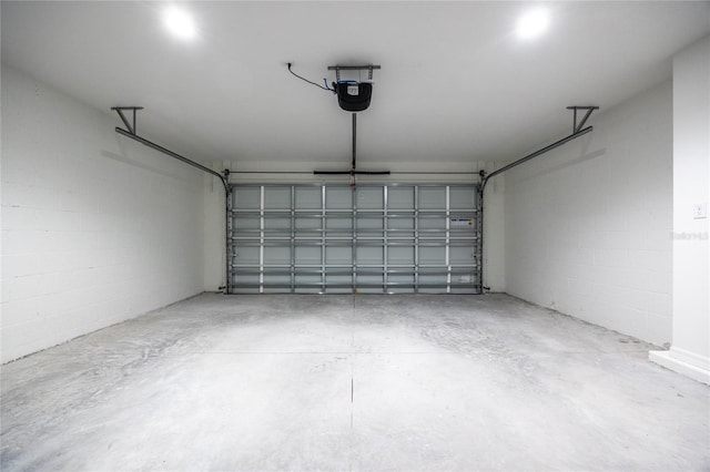 garage with a garage door opener and concrete block wall