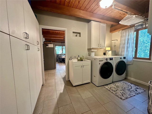 clothes washing area featuring cabinet space, washer and clothes dryer, wood ceiling, and light tile patterned flooring