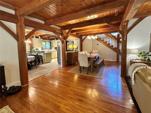 dining area with a chandelier, light wood-type flooring, stairs, beamed ceiling, and wooden ceiling