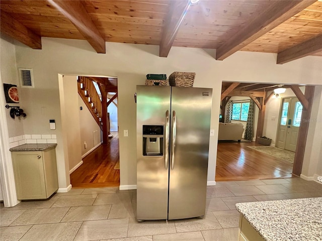 kitchen with stainless steel refrigerator with ice dispenser, baseboards, beamed ceiling, light tile patterned flooring, and arched walkways