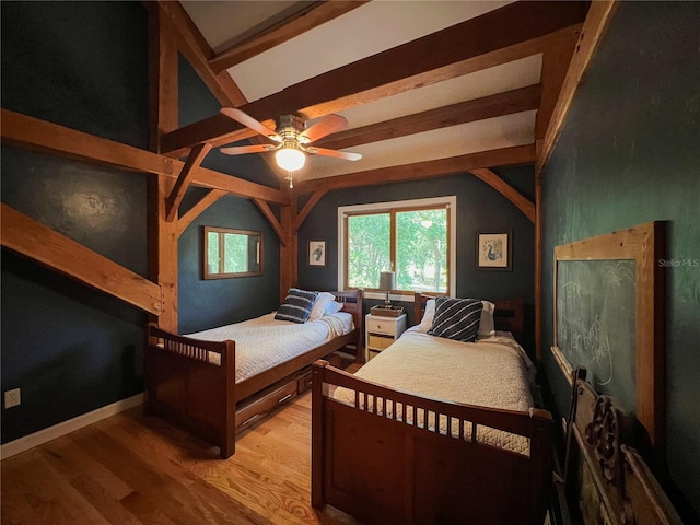 bedroom with wood finished floors, beamed ceiling, and ceiling fan