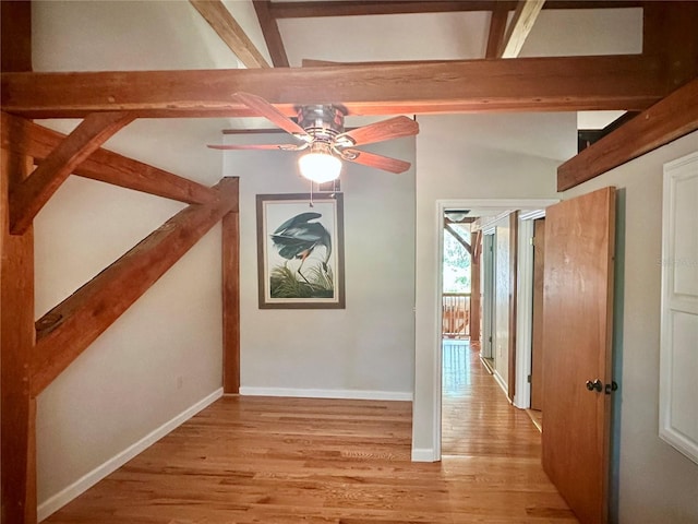 hall featuring light wood-style floors, beamed ceiling, and baseboards