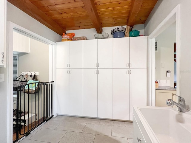 interior space featuring wood ceiling, beam ceiling, light countertops, a sink, and white cabinets