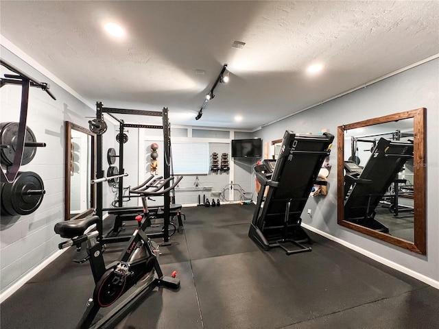 exercise room featuring a textured ceiling and baseboards