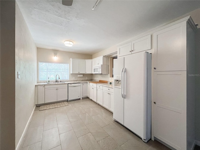 kitchen with white appliances, a sink, light countertops, white cabinets, and baseboards