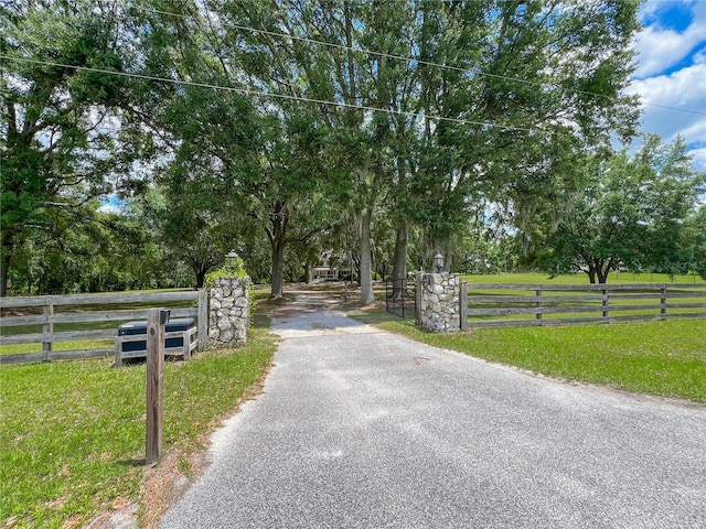 view of asphalt driveway featuring a gated entry
