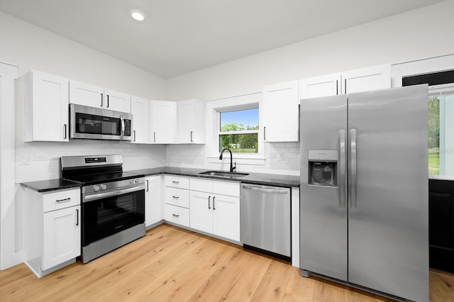 kitchen featuring appliances with stainless steel finishes, a sink, plenty of natural light, white cabinets, and recessed lighting