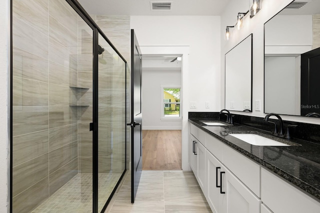 bathroom with a shower stall, double vanity, and baseboards