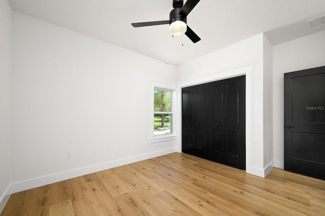 unfurnished bedroom featuring light wood-style flooring, baseboards, a ceiling fan, and a closet