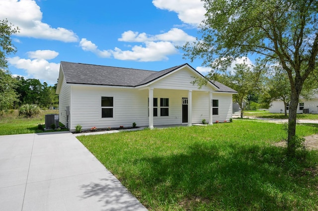 view of front of home with central AC, roof with shingles, and a front yard