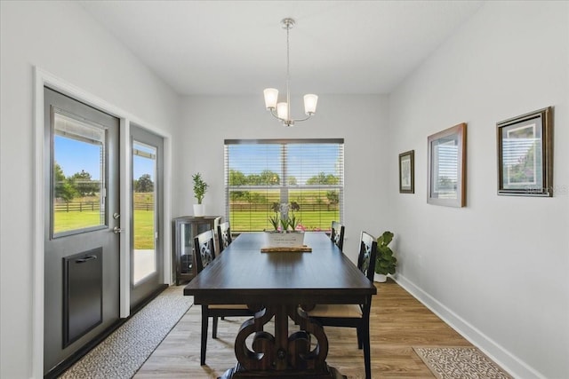 dining space with a chandelier, baseboards, and light wood-style floors