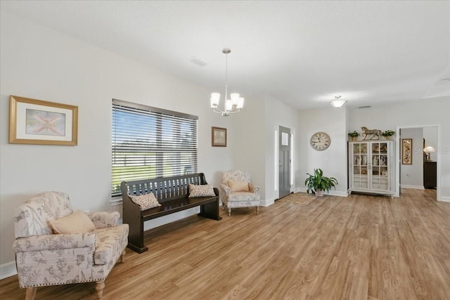 sitting room with a chandelier, light wood-style floors, and baseboards