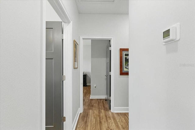 corridor featuring light wood-type flooring and baseboards