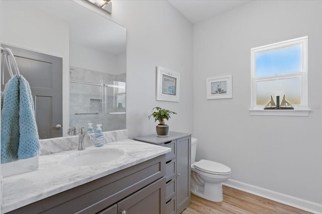 full bath featuring wood finished floors, a shower stall, toilet, vanity, and baseboards