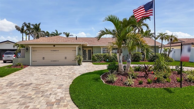 1120 81st St S, Saint Petersburg, FL 33707 - ranch-style house with decorative driveway, stucco siding, an attached garage, a front lawn, and french doors
