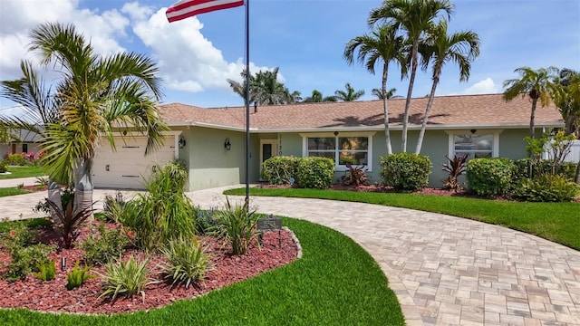 1120 81st St S, Saint Petersburg, FL 33707 - ranch-style home with curved driveway, stucco siding, an attached garage, and a front lawn