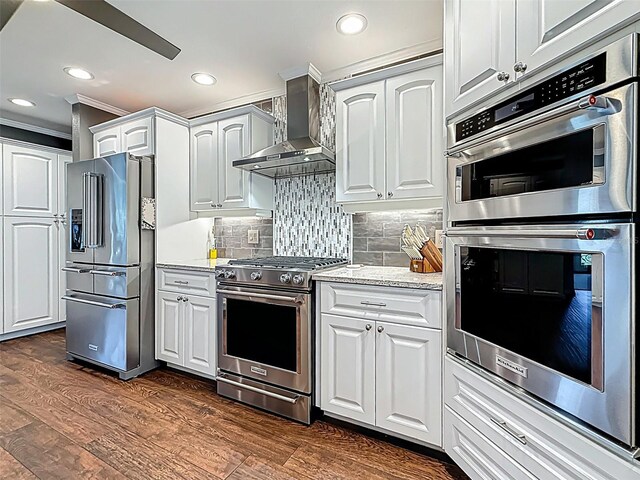 1120 81st St S, Saint Petersburg, FL 33707 - kitchen with high end appliances, wall chimney range hood, crown molding, white cabinetry, and dark wood-style flooring