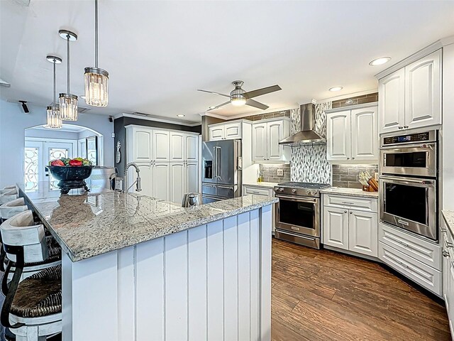 1120 81st St S, Saint Petersburg, FL 33707 - kitchen with high end appliances, wall chimney exhaust hood, a kitchen breakfast bar, white cabinetry, and recessed lighting