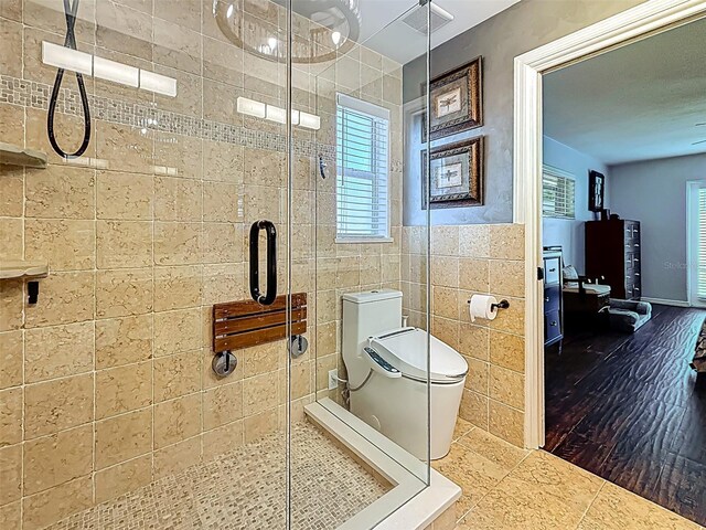 1120 81st St S, Saint Petersburg, FL 33707 - bathroom featuring tile walls, toilet, and a stall shower