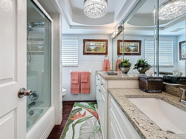 1120 81st St S, Saint Petersburg, FL 33707 - full bathroom featuring vanity, tile walls, toilet, plenty of natural light, and a chandelier