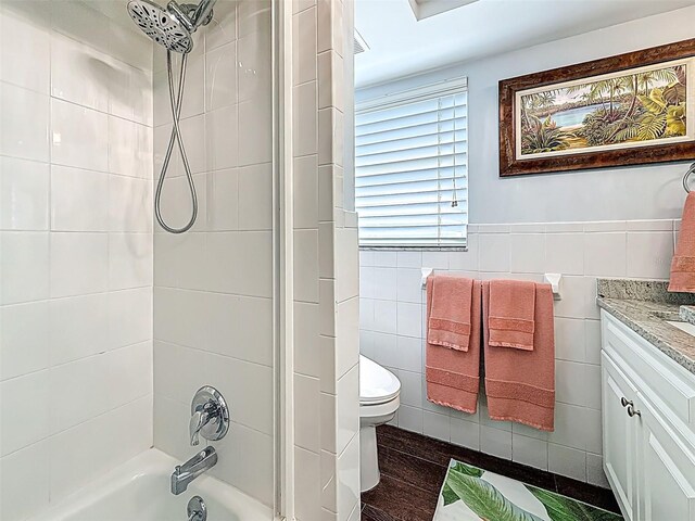1120 81st St S, Saint Petersburg, FL 33707 - bathroom featuring tile walls, bathing tub / shower combination, vanity, and toilet