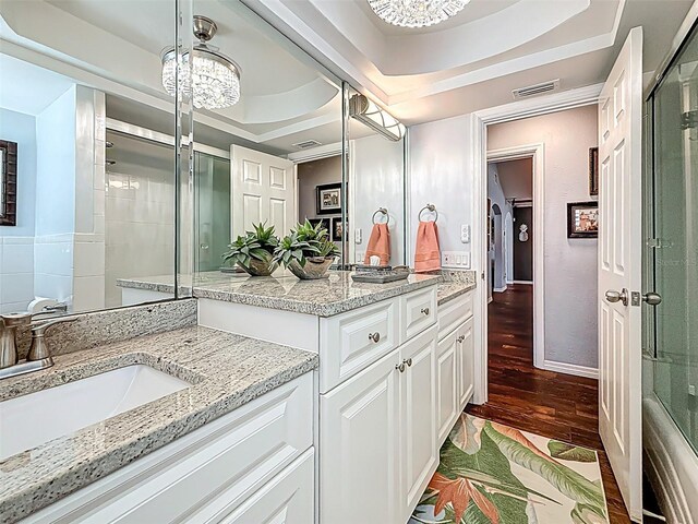 1120 81st St S, Saint Petersburg, FL 33707 - bathroom featuring wood finished floors, vanity, a tray ceiling, and baseboards