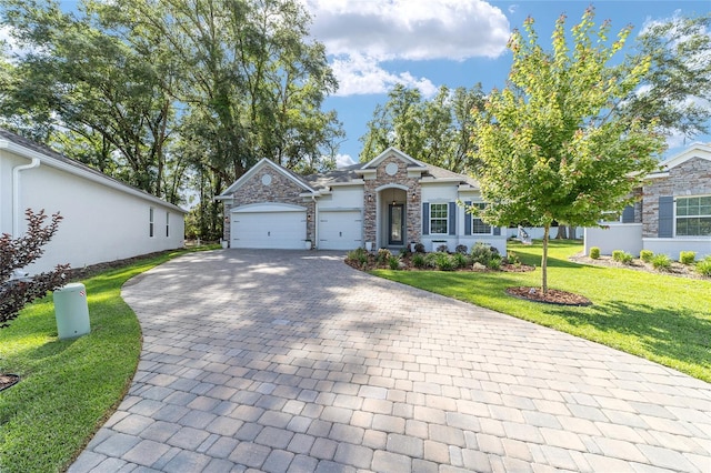 view of front of home featuring stone siding, decorative driveway, a front yard, and an attached garage