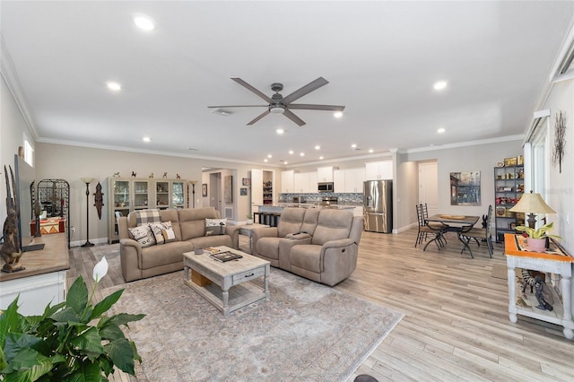living area featuring recessed lighting, ceiling fan, crown molding, light wood-style floors, and baseboards