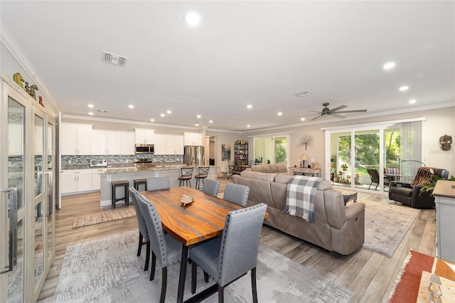 dining area with ornamental molding, light wood-type flooring, ceiling fan, and recessed lighting