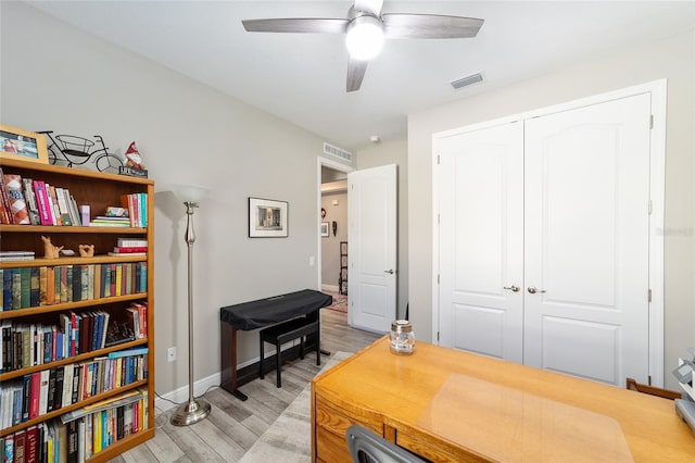 office area with light wood-style flooring, ceiling fan, and baseboards