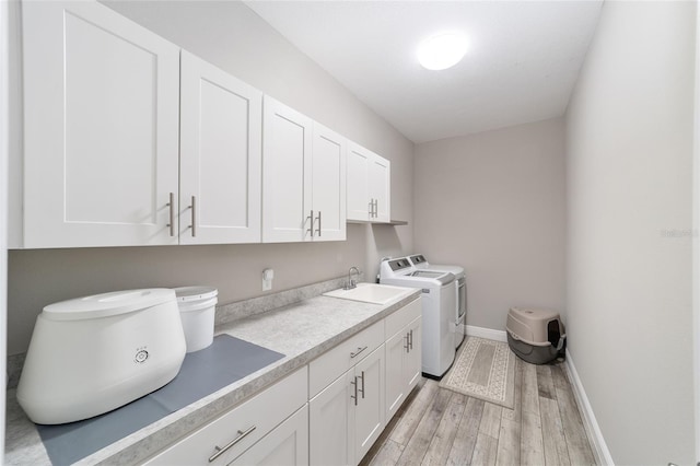 laundry room with cabinet space, washing machine and clothes dryer, light wood-type flooring, and baseboards