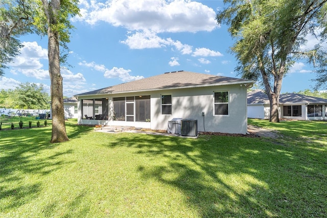 rear view of house with a sunroom, a yard, stucco siding, and central air condition unit