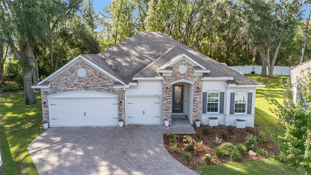 view of front of home with stone siding, decorative driveway, an attached garage, stucco siding, and a shingled roof