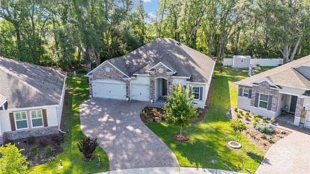 view of front of home featuring stone siding, an attached garage, decorative driveway, a front yard, and stucco siding