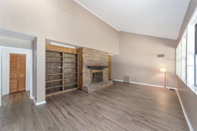 13207 SW Williston Rd, Micanopy, FL 32667 - unfurnished living room featuring baseboards, wood finished floors, high vaulted ceiling, a fireplace, and built in features