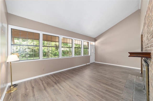 13207 SW Williston Rd, Micanopy, FL 32667 - unfurnished living room with baseboards, wood finished floors, a brick fireplace, and high vaulted ceiling