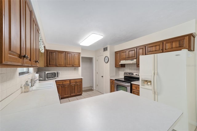 13207 SW Williston Rd, Micanopy, FL 32667 - kitchen with stainless steel appliances, under cabinet range hood, tasteful backsplash, light countertops, and a sink
