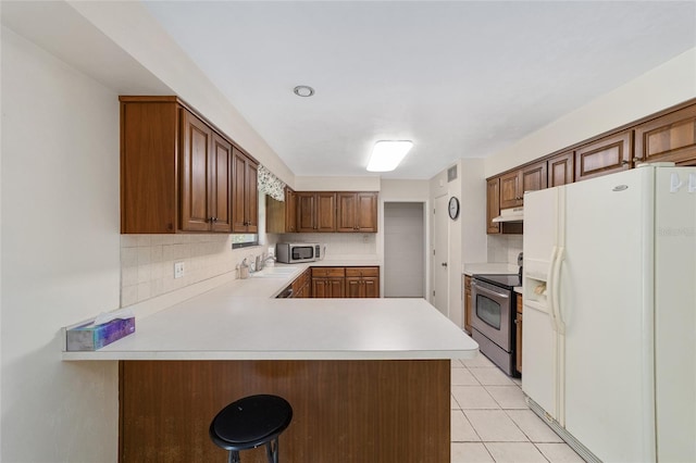 13207 SW Williston Rd, Micanopy, FL 32667 - kitchen with stainless steel appliances, under cabinet range hood, backsplash, light countertops, and a sink
