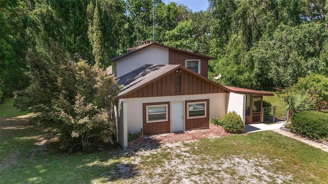13207 SW Williston Rd, Micanopy, FL 32667 - view of front of property with a front lawn, a view of trees, and board and batten siding
