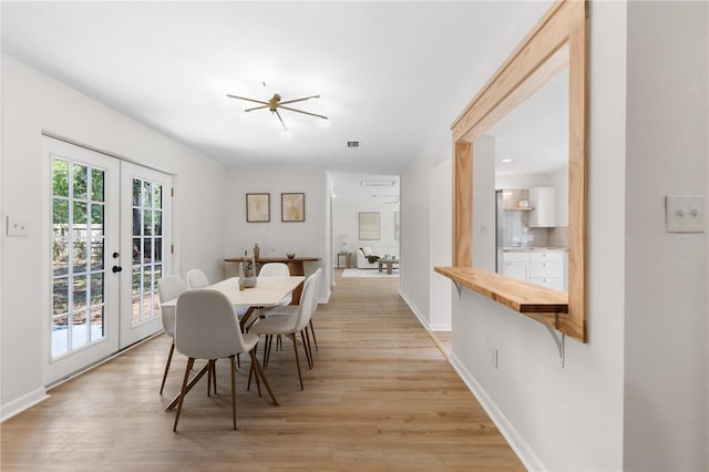 dining area featuring french doors, light wood-type flooring, and baseboards