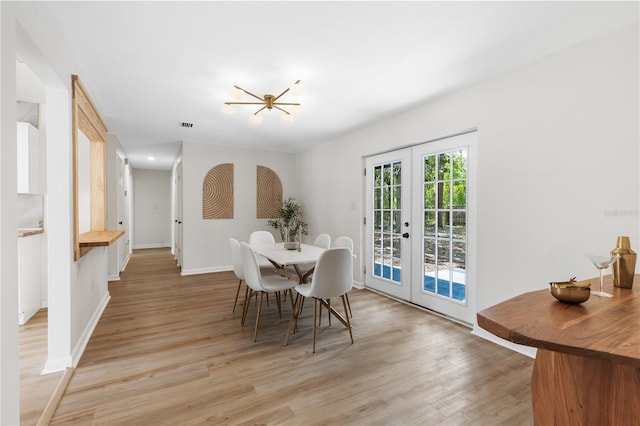 dining space with french doors, light wood-style flooring, a chandelier, and baseboards