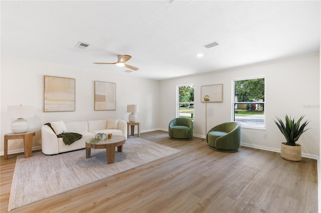 living area featuring light wood-style flooring, baseboards, and ceiling fan