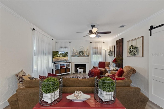 914 S Main St, Trenton, FL 32693 - living room featuring ceiling fan, crown molding, a barn door, a fireplace, and wood finished floors