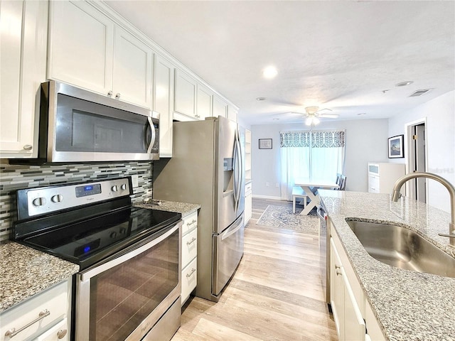 4000 SW 23rd St Unit 3-305, Gainesville, FL 32608 - kitchen featuring appliances with stainless steel finishes, a sink, light wood-style flooring, decorative backsplash, and white cabinets