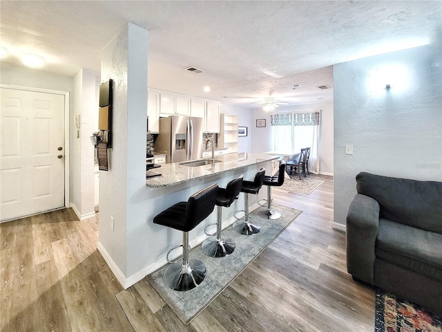 4000 SW 23rd St Unit 3-305, Gainesville, FL 32608 - kitchen with stainless steel fridge with ice dispenser, a sink, a breakfast bar, white cabinets, and light wood finished floors