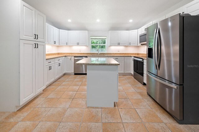 3046 SE 134th St, Starke, FL 32091 - kitchen with appliances with stainless steel finishes, a sink, a kitchen island, white cabinets, and recessed lighting